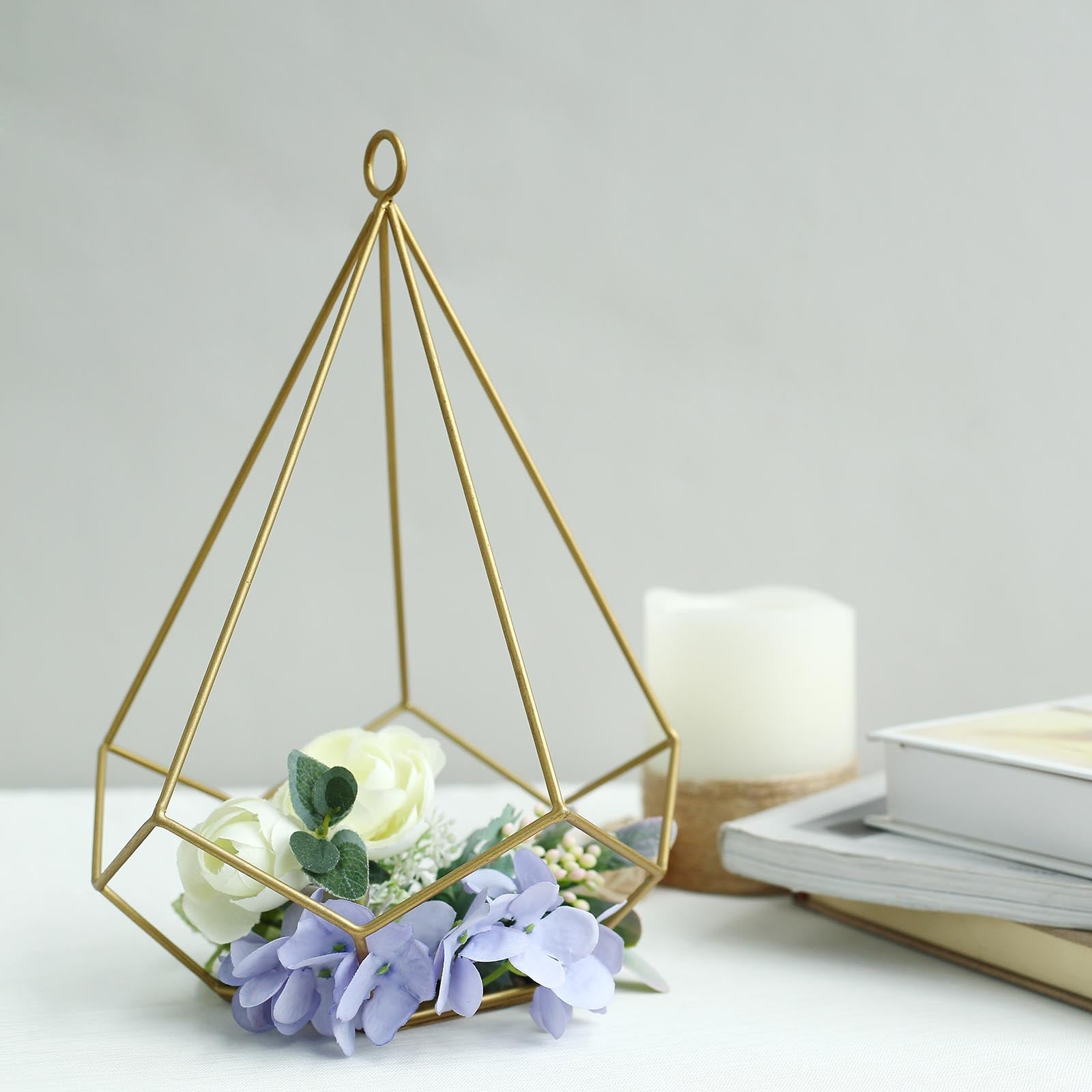 Gold metal geometric candle holder with flowers and a candle.