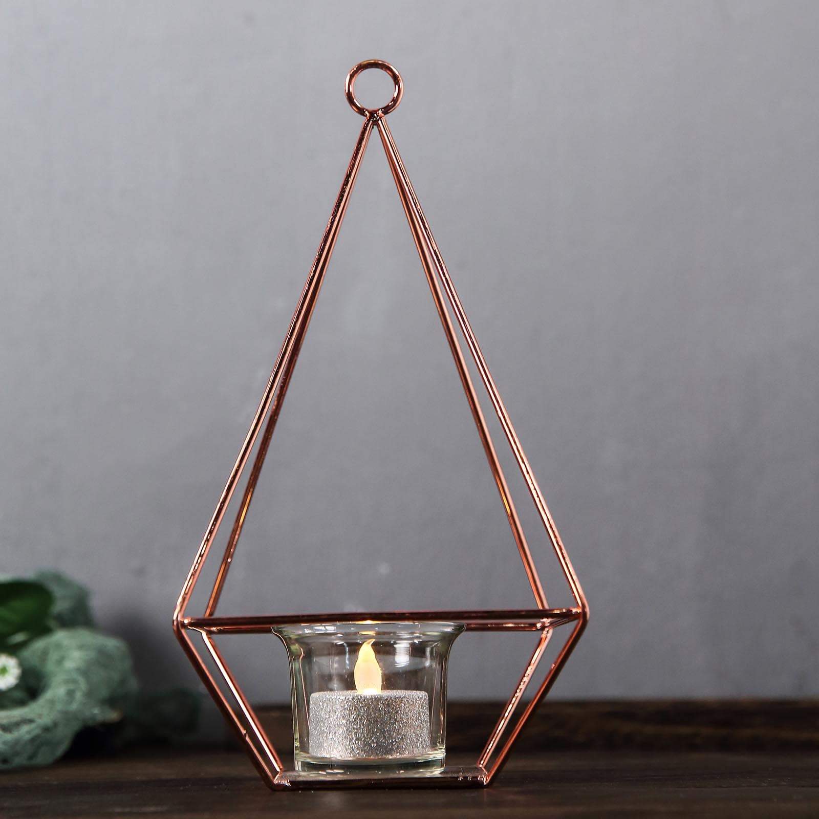 Rose gold pyramid-shaped tealight candle holder with open frame design.