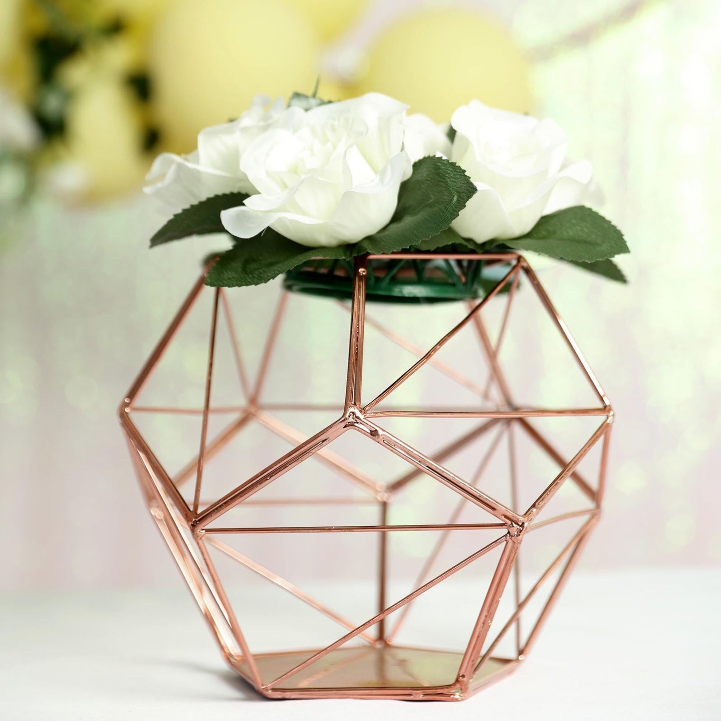 Rose gold geometric pentagon prism tealight candle holder with white flowers.