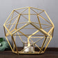 Gold metal pentagon prism tealight candle holder with geometric design.