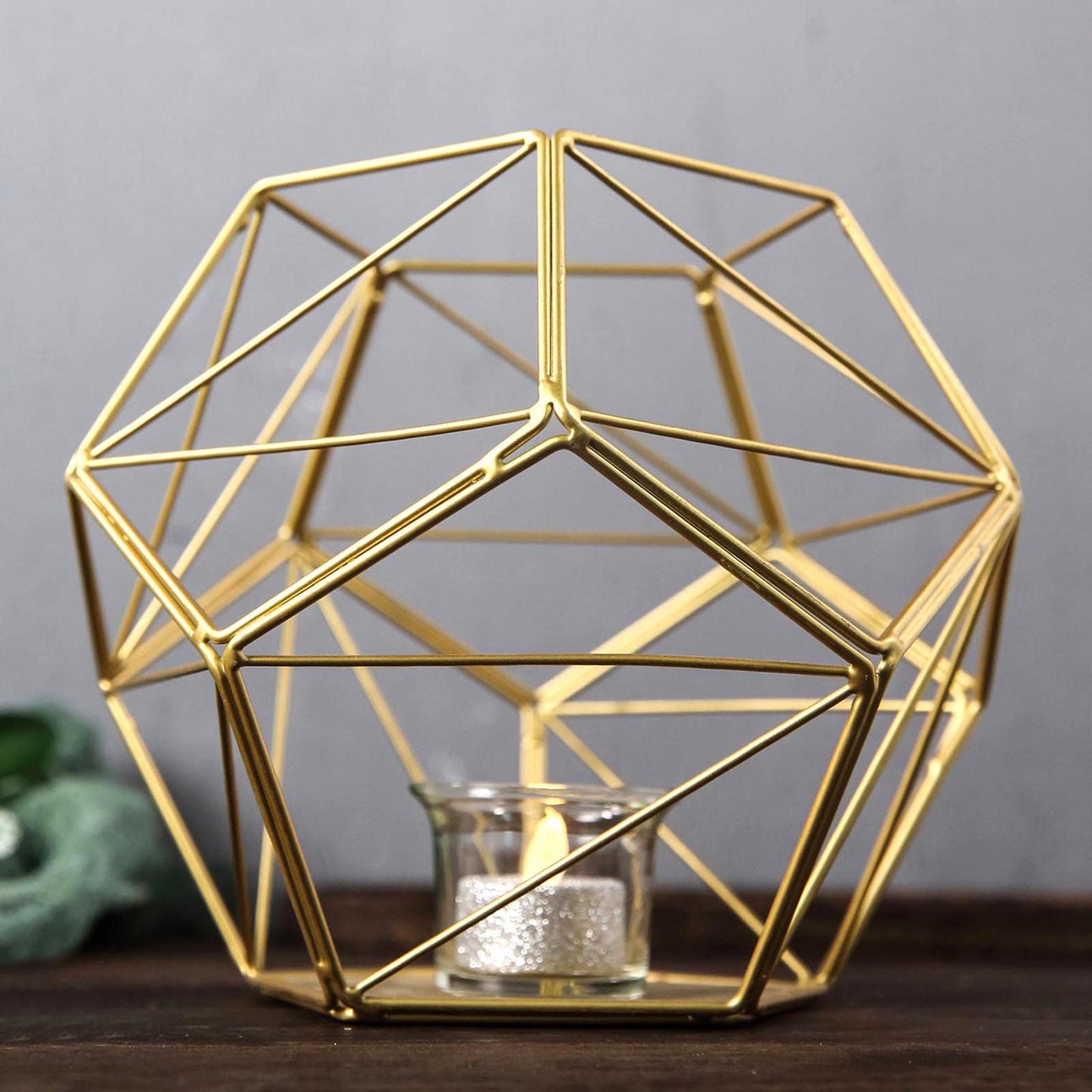 Gold metal pentagon prism tealight candle holder with geometric design.