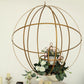 Gold open frame centerpiece ball with floral display and candle holder.