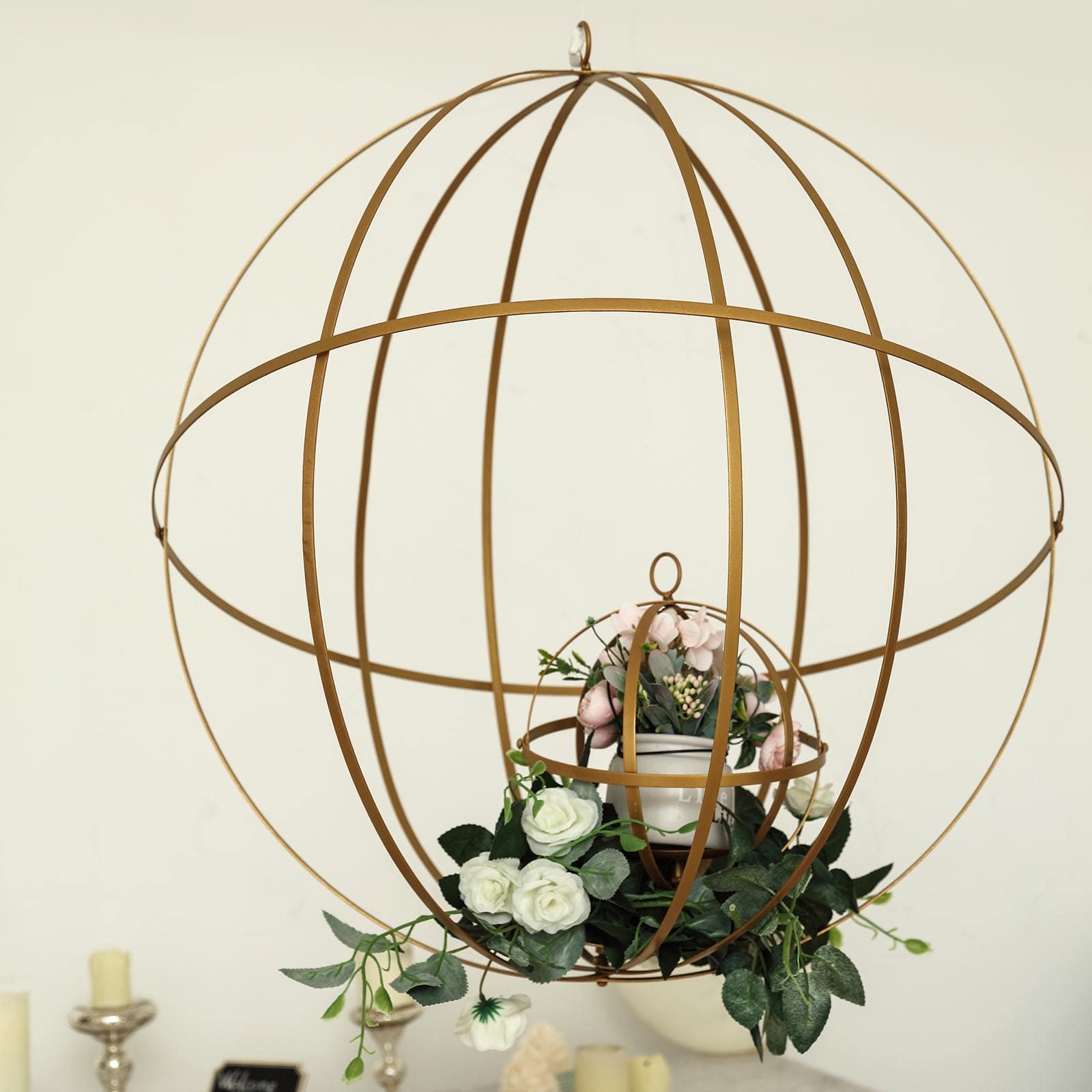 Gold open frame centerpiece ball with floral display and candle holder.