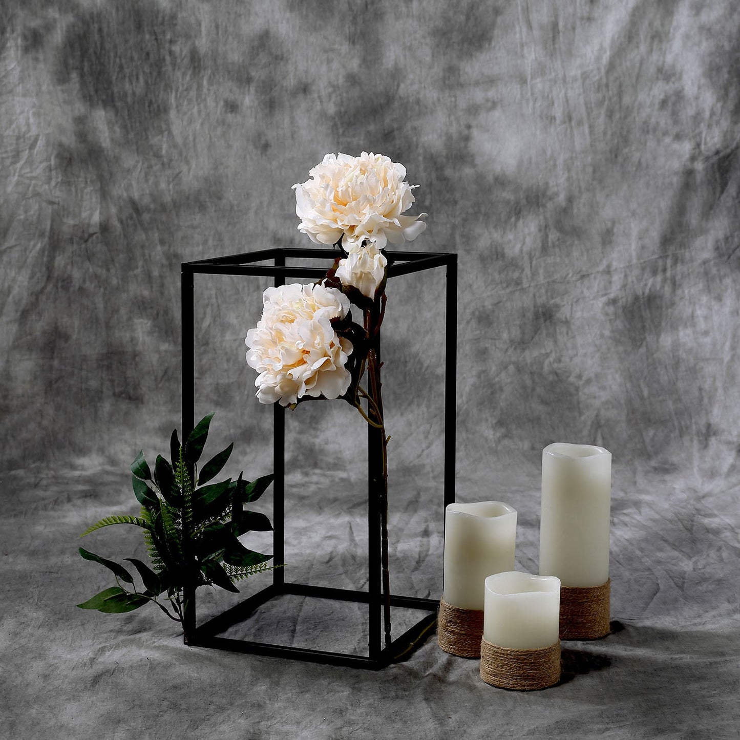 Matte black geometric flower stand with white flowers and candles.