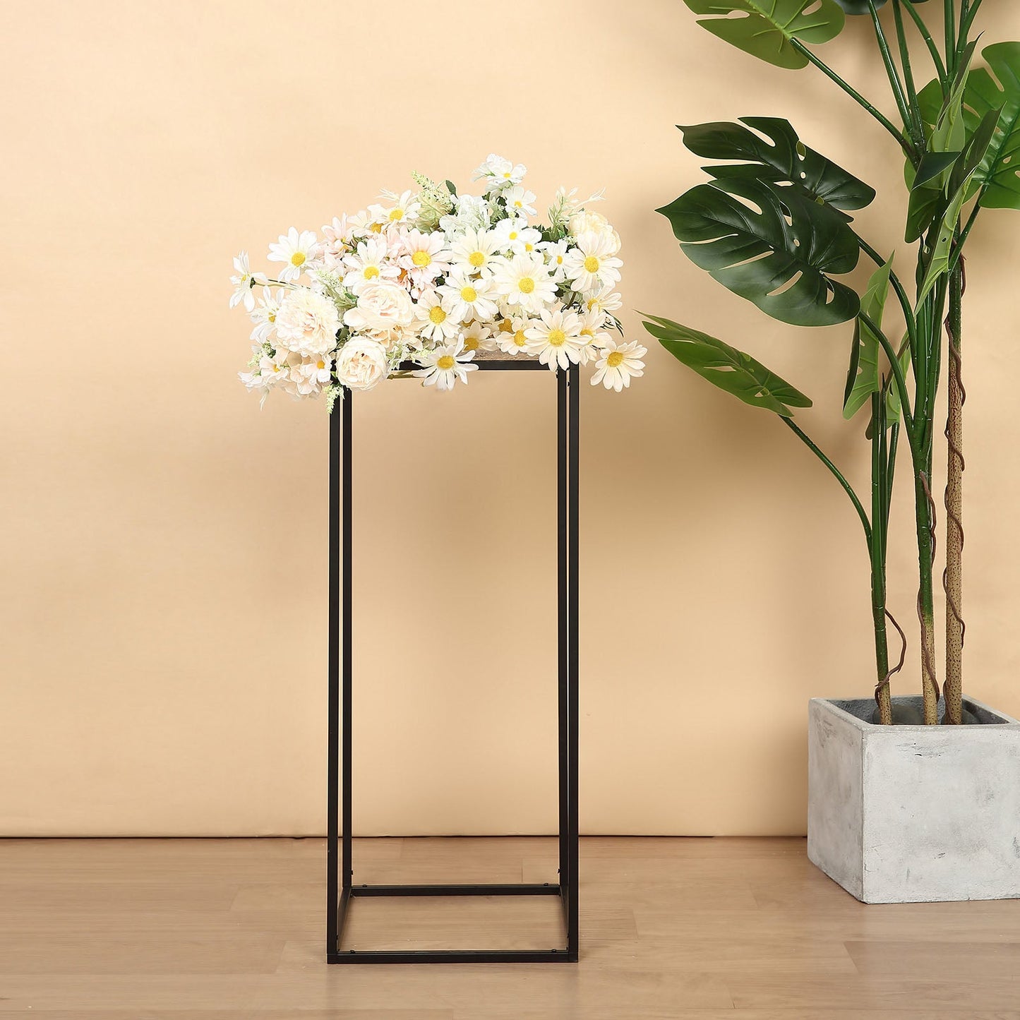 Matte black metal wedding flower stand with floral arrangement on top.