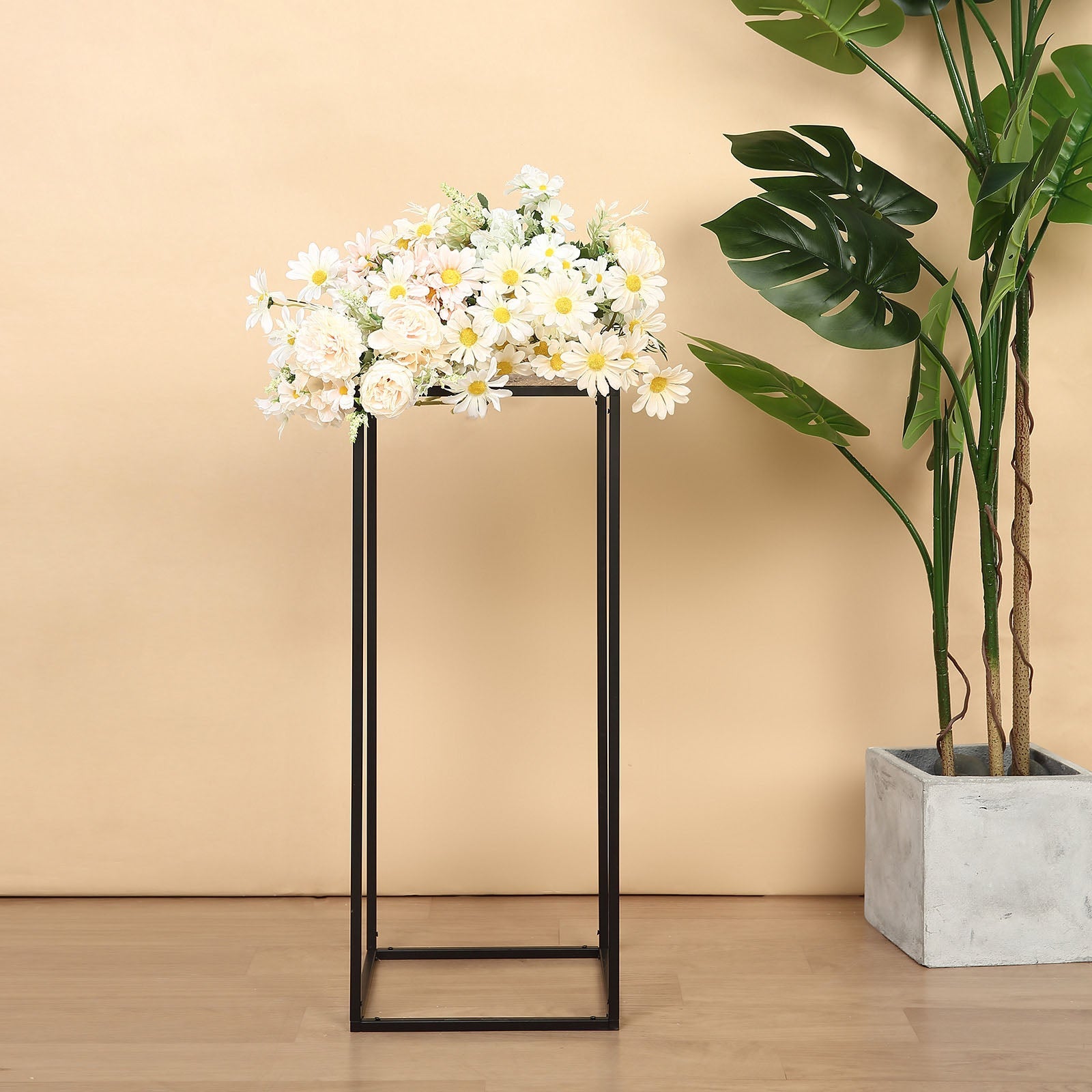 Matte black metal wedding flower stand with floral arrangement on top.
