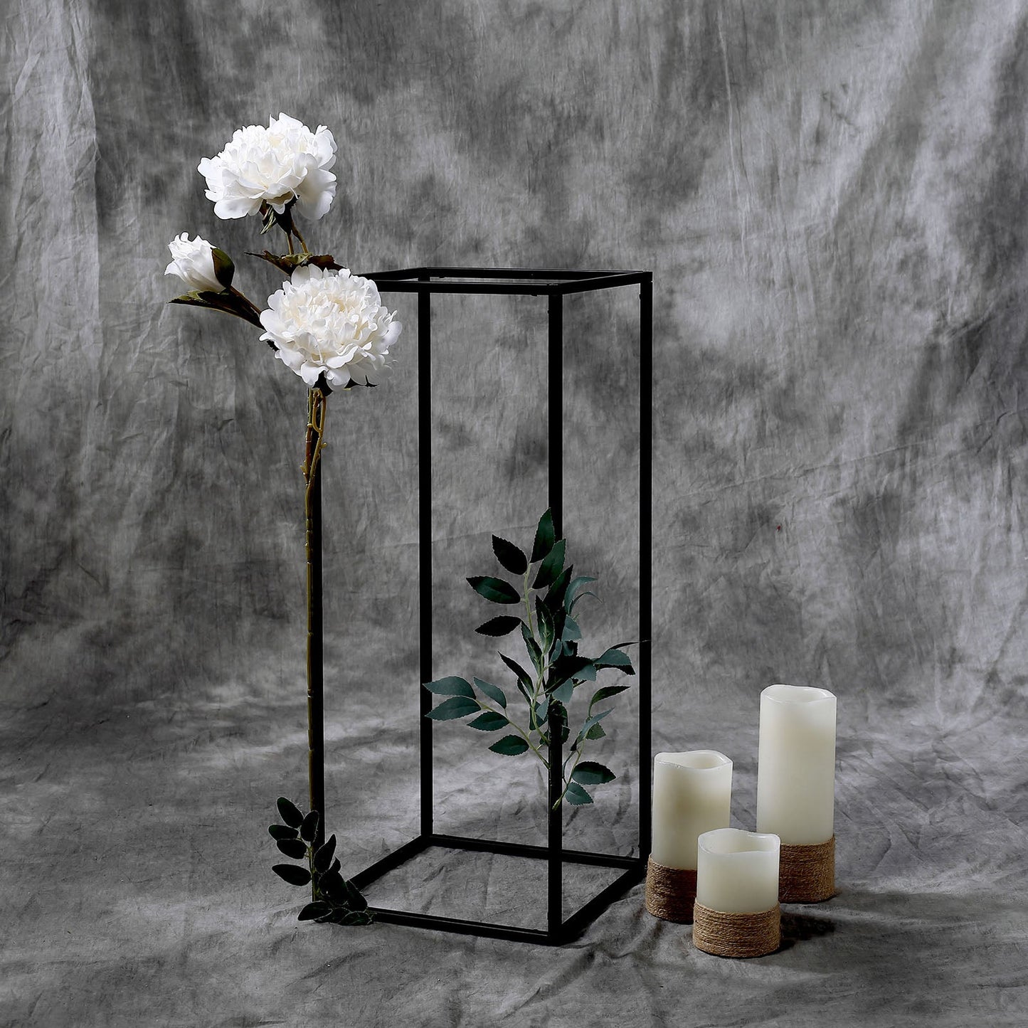 Matte black geometric flower stand with white peonies and candles.
