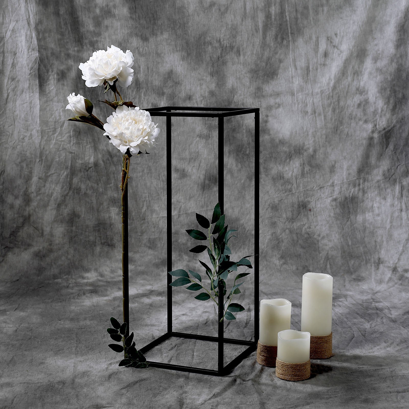Matte black geometric flower stand with white peonies and candles.