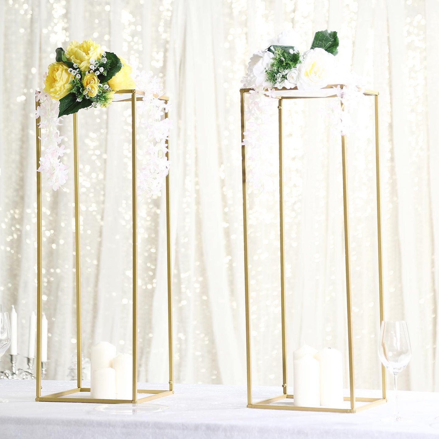 Gold metal geometric flower stands with floral arrangements and candles.