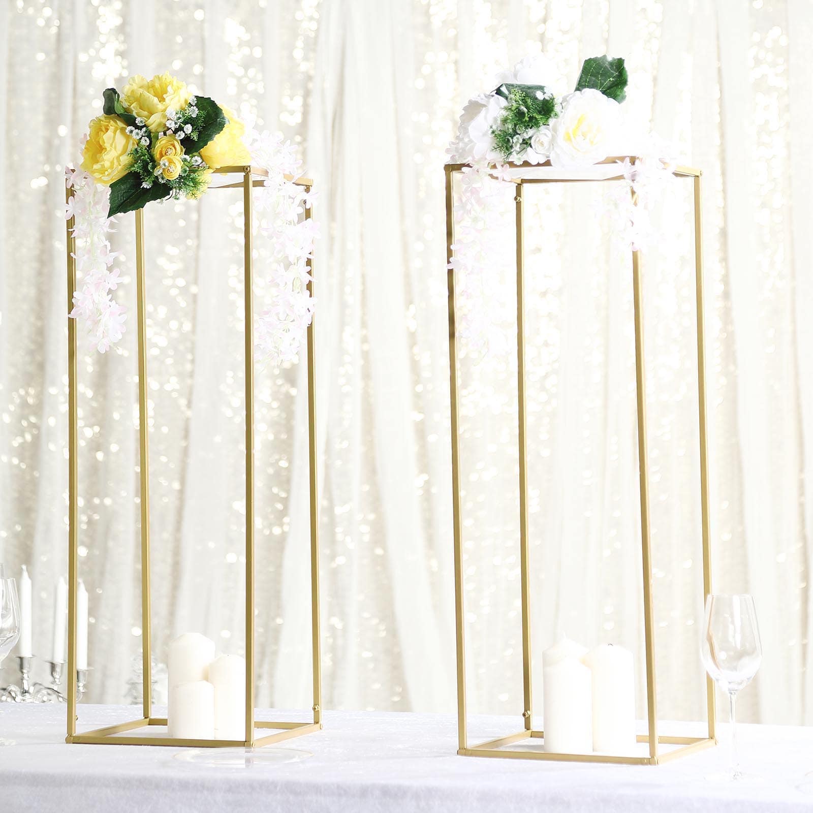 Gold metal geometric flower stands with floral arrangements and candles.