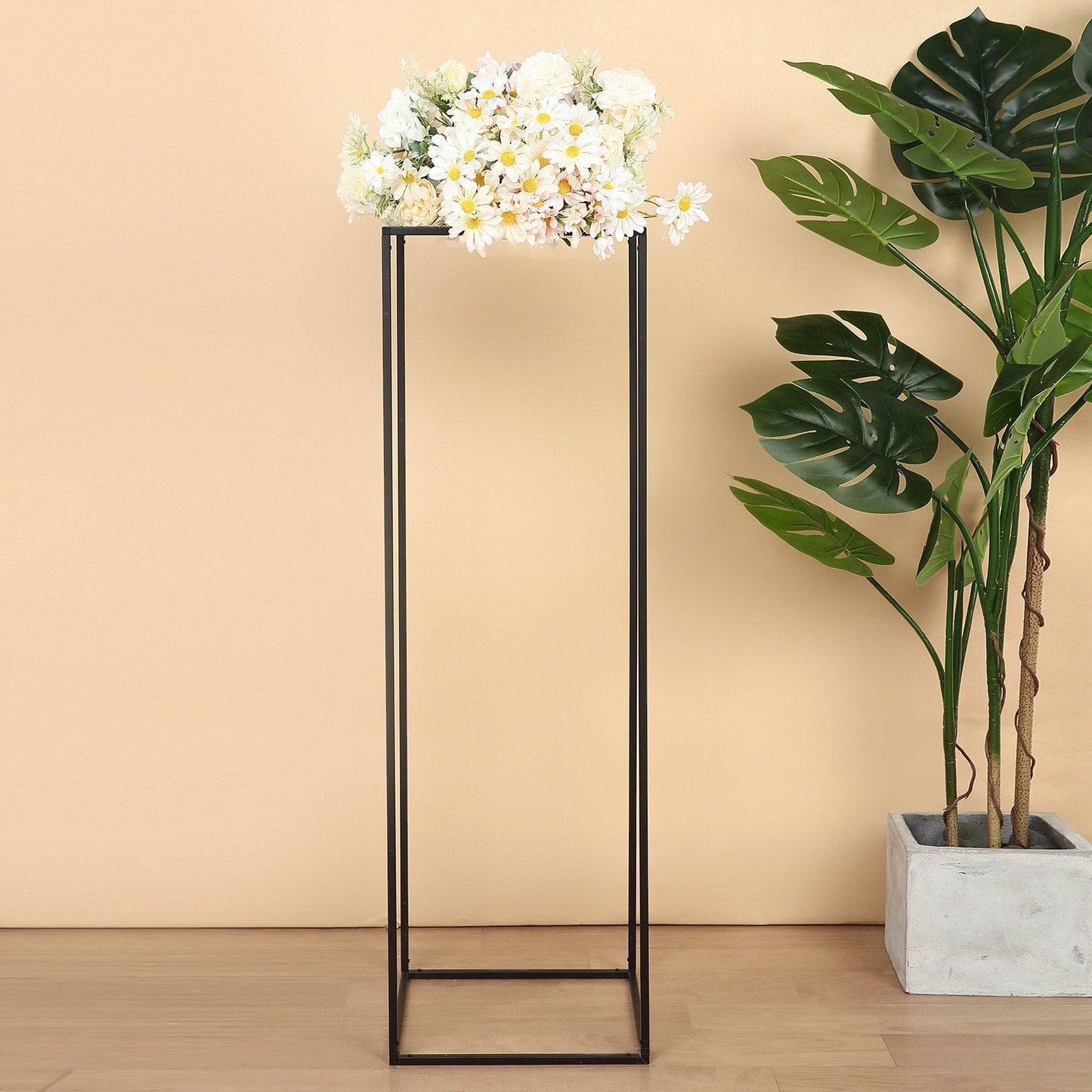 Matte black metal wedding flower stand with white flowers on top.