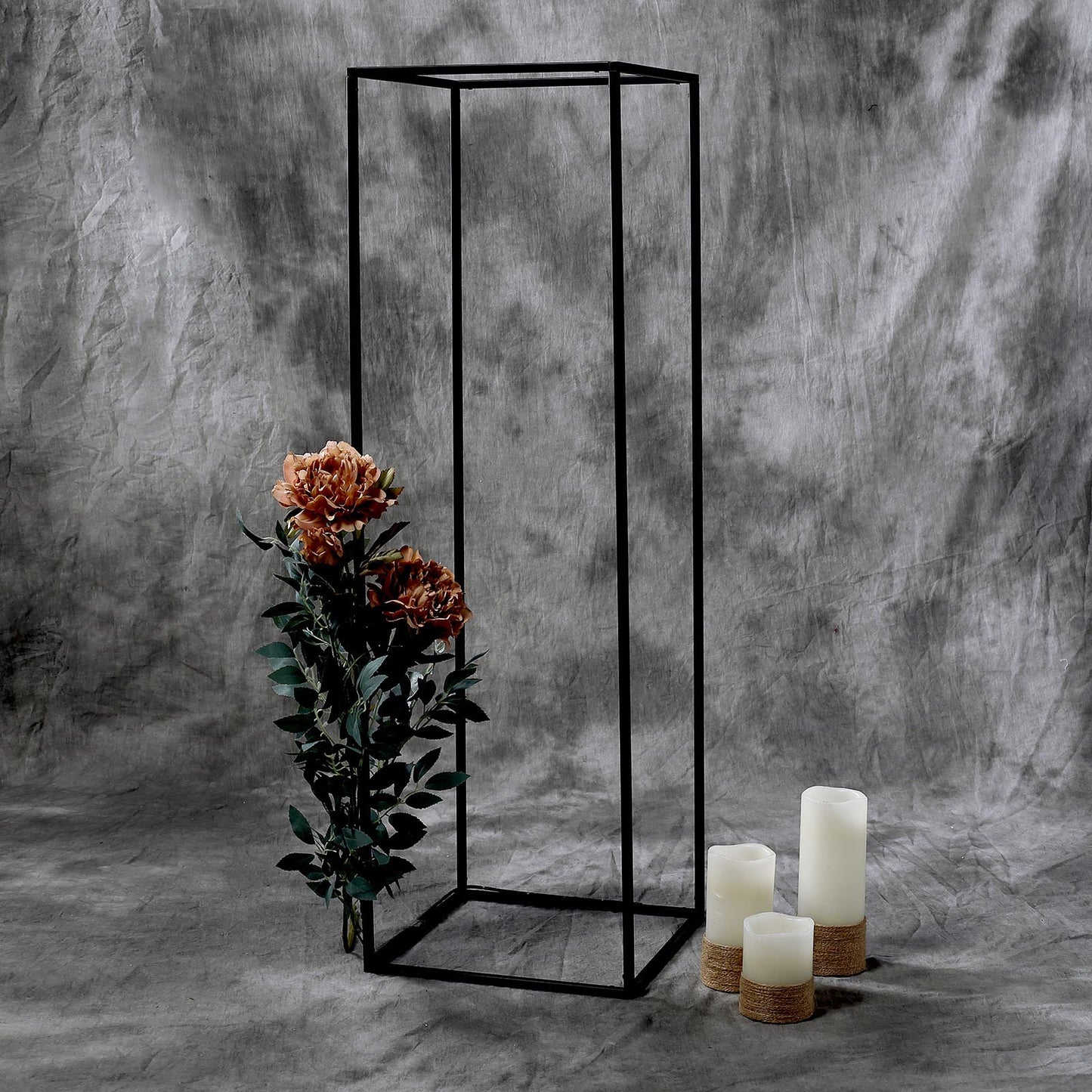 Matte black geometric flower stand with floral arrangement and candles.