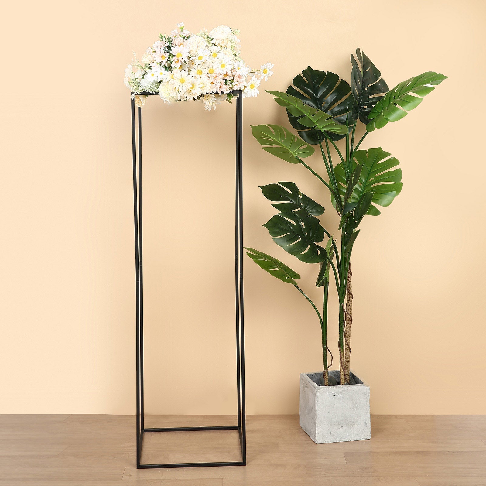 Matte black metal wedding flower stand with floral arrangement on top.