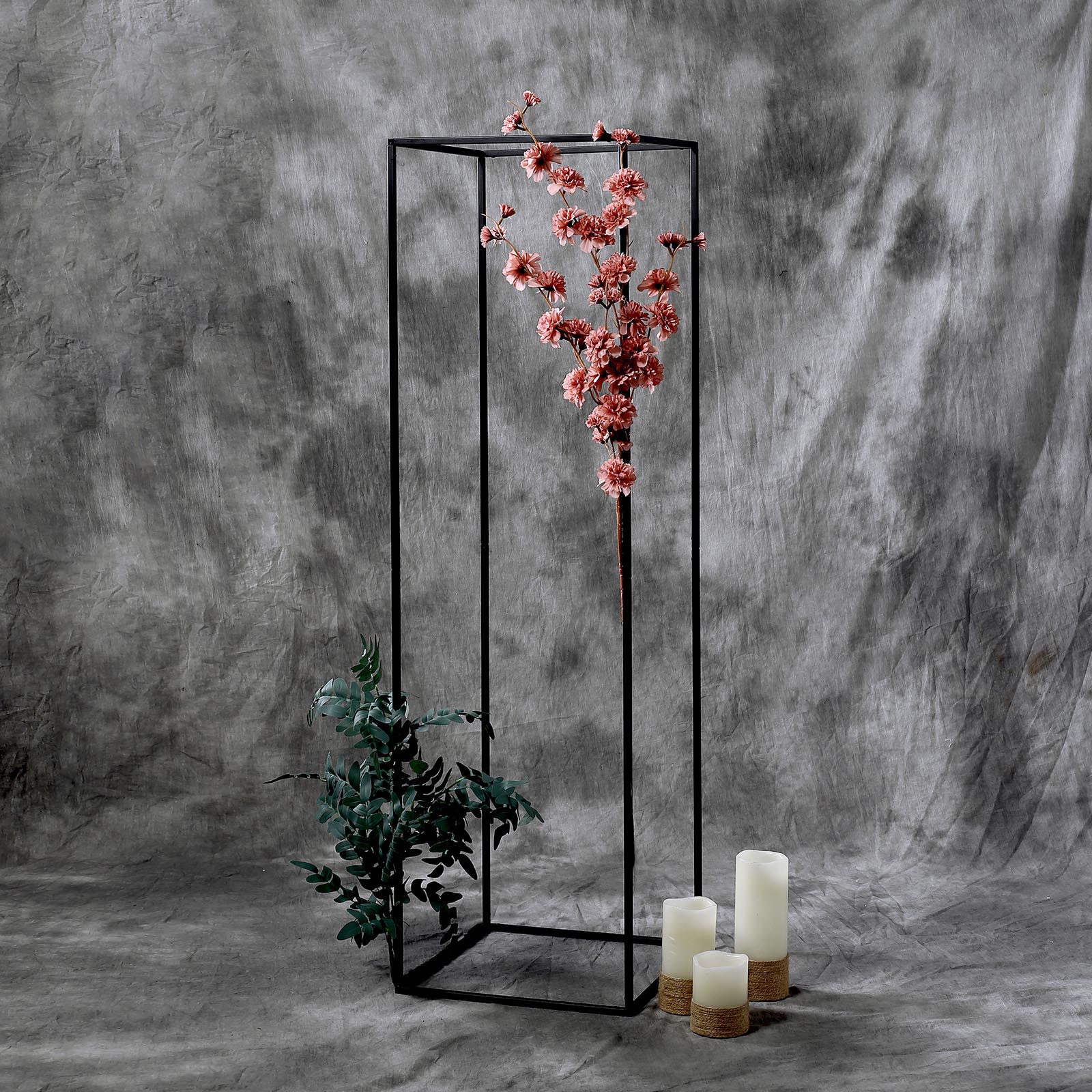 Matte black metal geometric flower stand with floral arrangement and candles.
