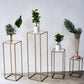 Clear acrylic square plexiglass sheets displayed on gold plant stands.