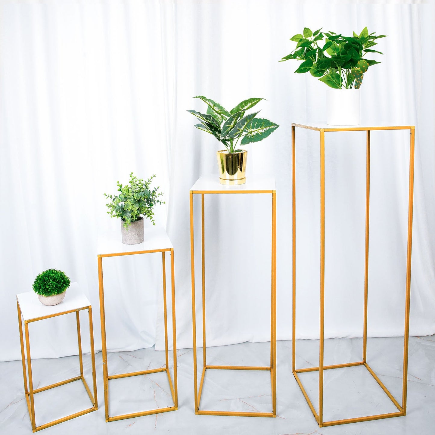 White acrylic square plexiglass sheets displayed on gold plant stands.