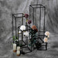 Matte black metal flower stands with floral arrangements and candles.