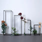 Matte black metal frame flower stands with artificial flowers and greenery.