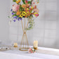 Gold metal geometric flower stand with vibrant floral arrangement.