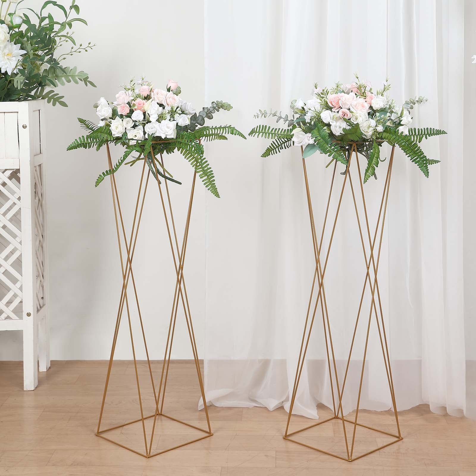 Gold geometric crisscross metal frame flower stands with floral arrangements.