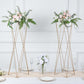 Gold geometric crisscross metal frame flower stands with elegant floral arrangements.