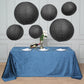 Black hanging paper lanterns in assorted sizes above a blue tablecloth.