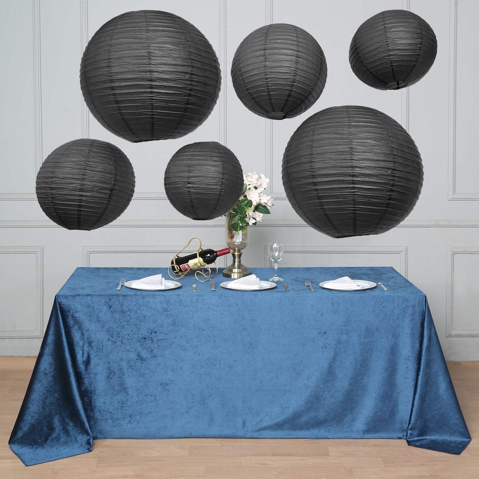 Black hanging paper lanterns in assorted sizes above a blue tablecloth.