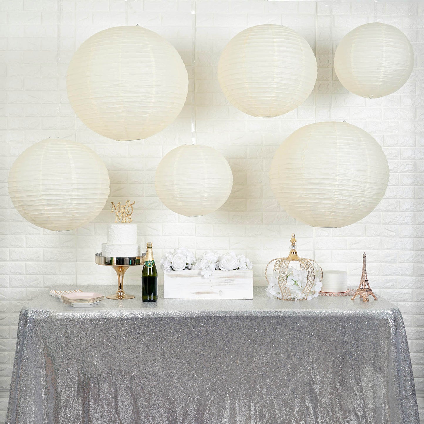 Cream hanging paper lanterns in assorted sizes displayed above a festive table.