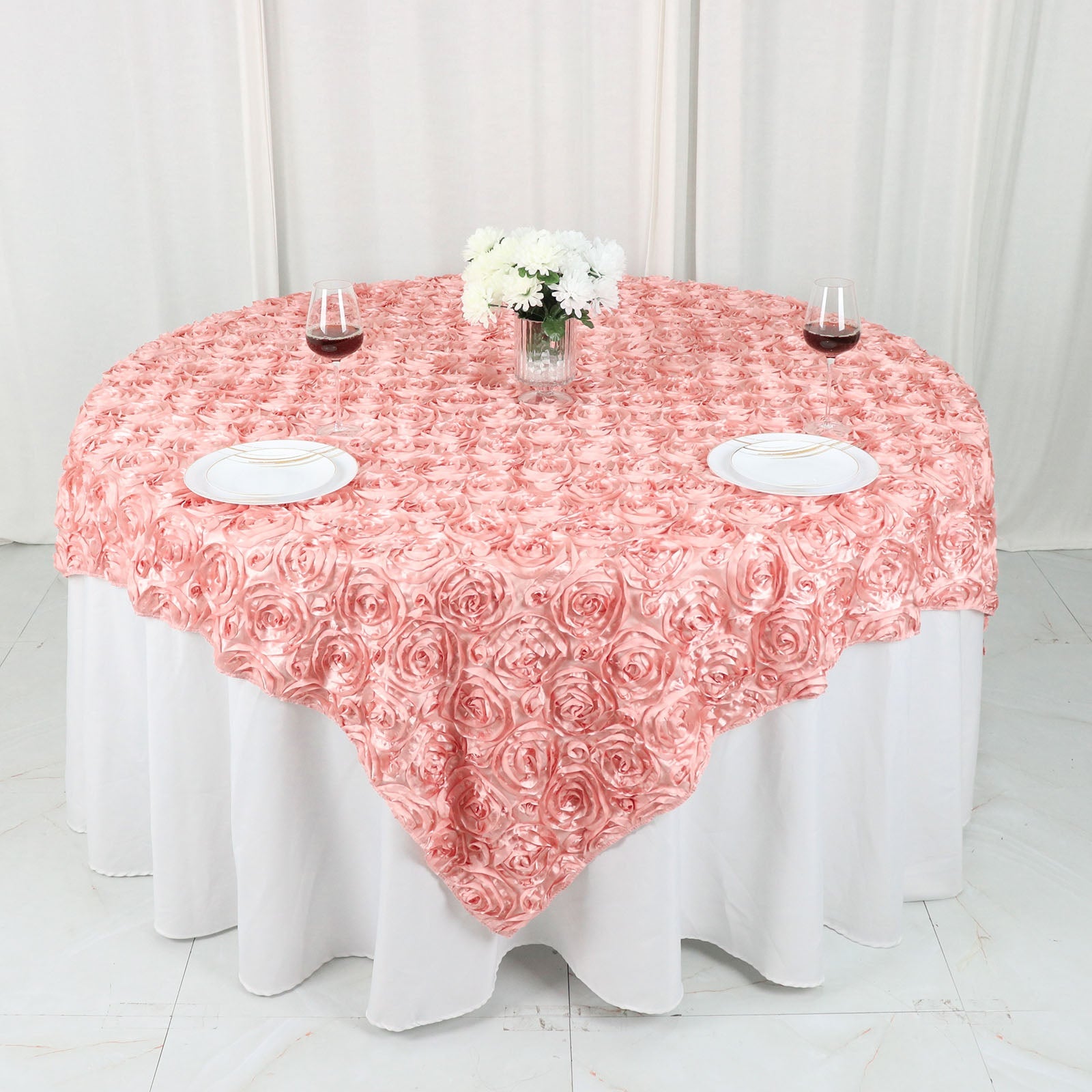 Dusty rose 3D rosette satin table overlay on a round table.