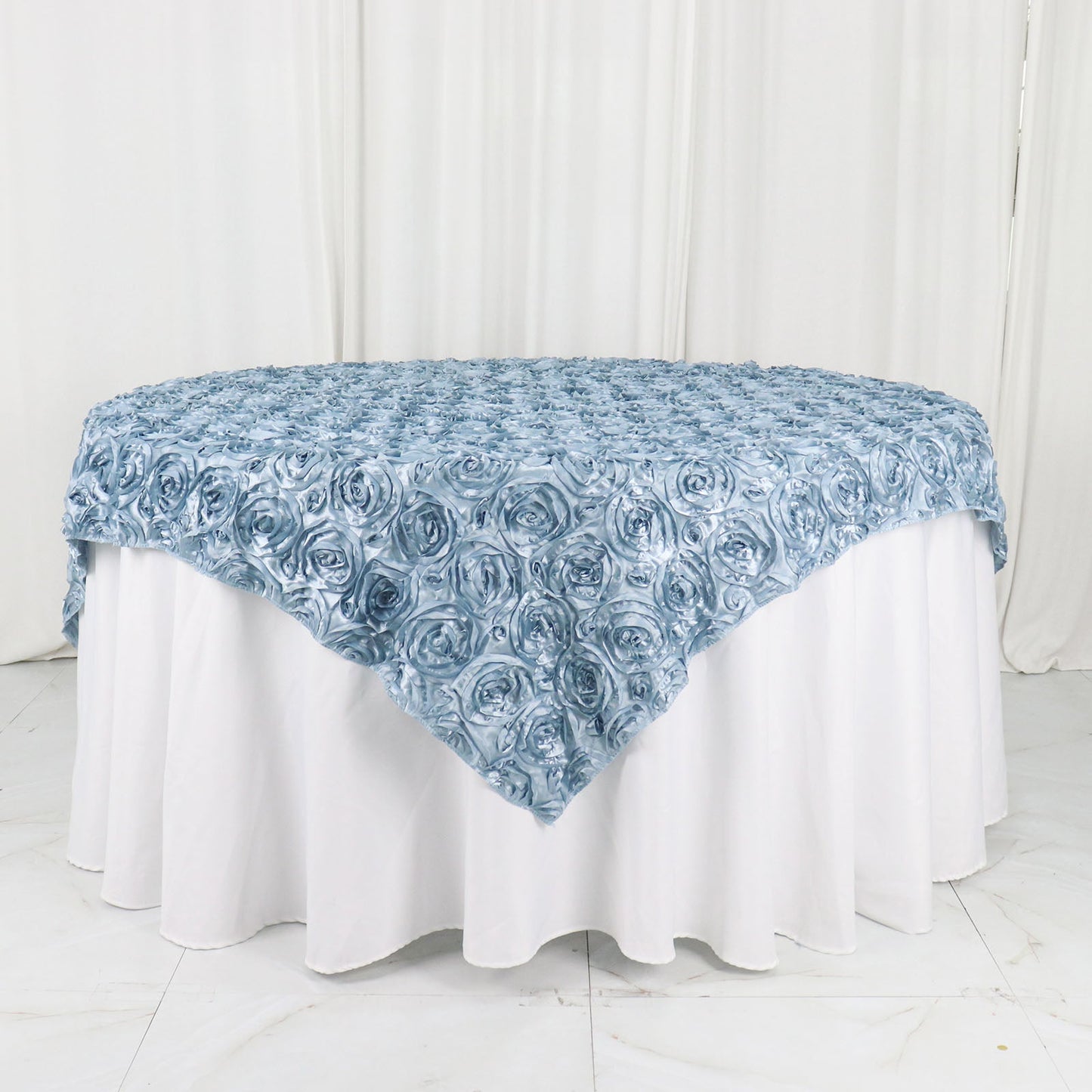 Dusty blue 3D rosette satin table overlay on a round table.