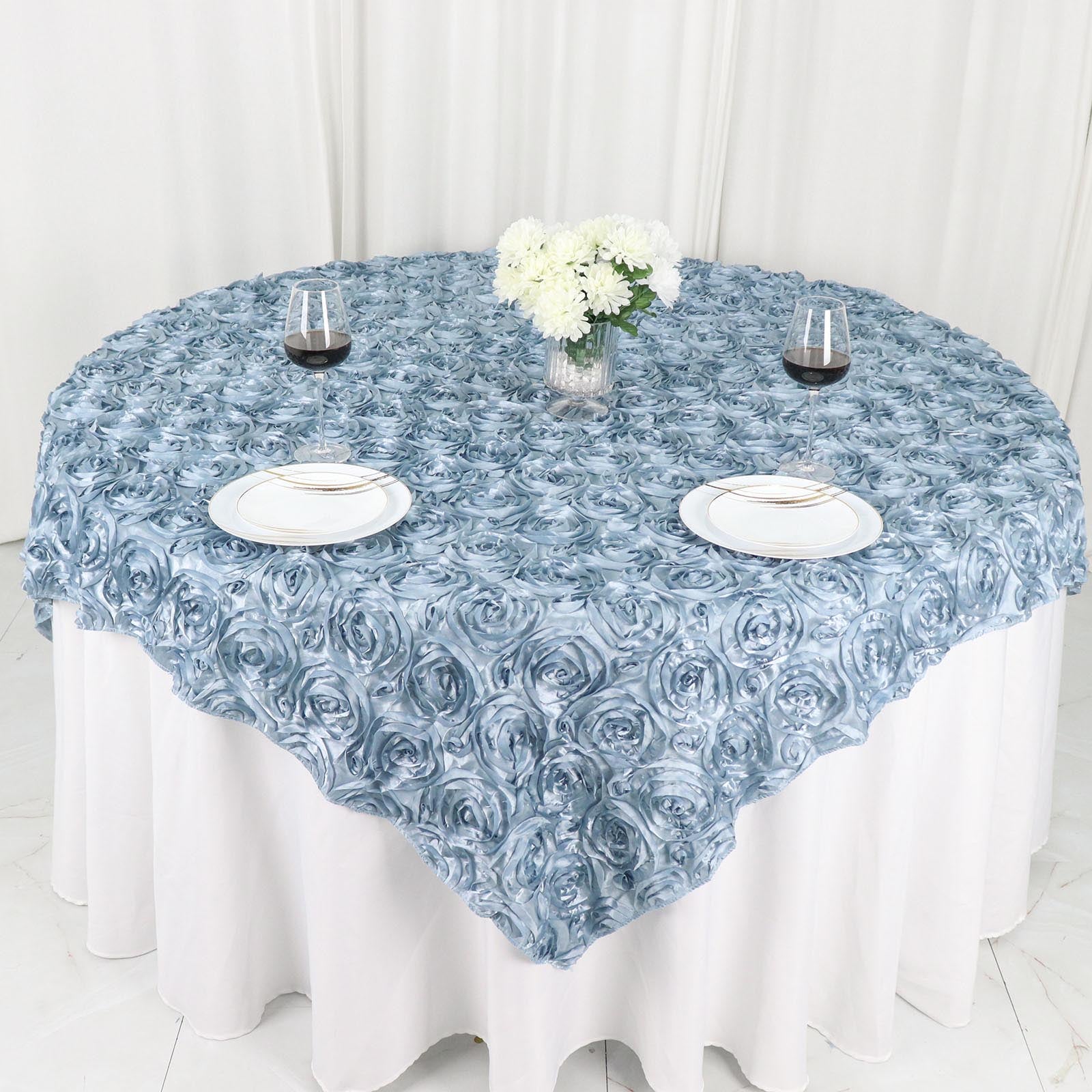 Dusty blue 3D rosette satin table overlay on round table with floral centerpiece.