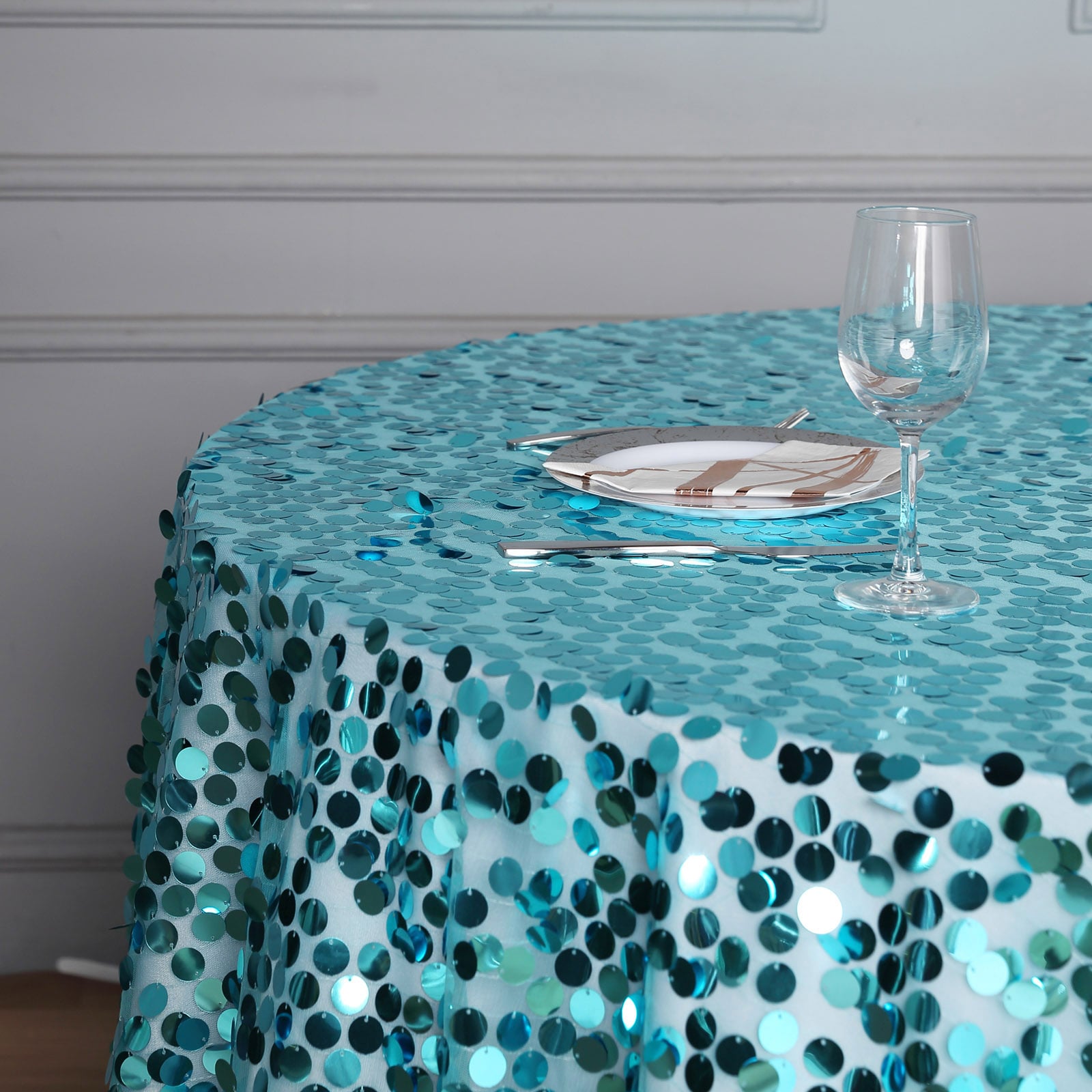 Turquoise sequin table overlay on a round table setting.