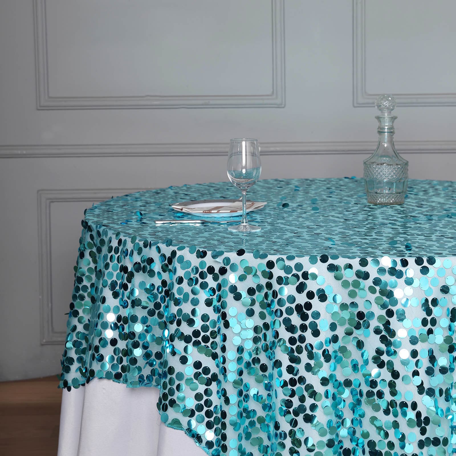 Turquoise sequin table overlay on a round table setting.