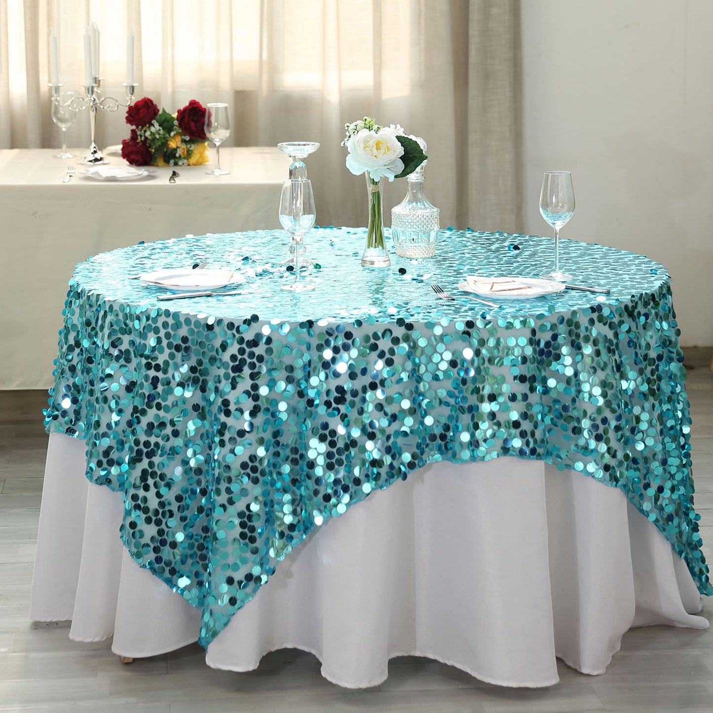 Turquoise sequin table overlay on a round table setting.