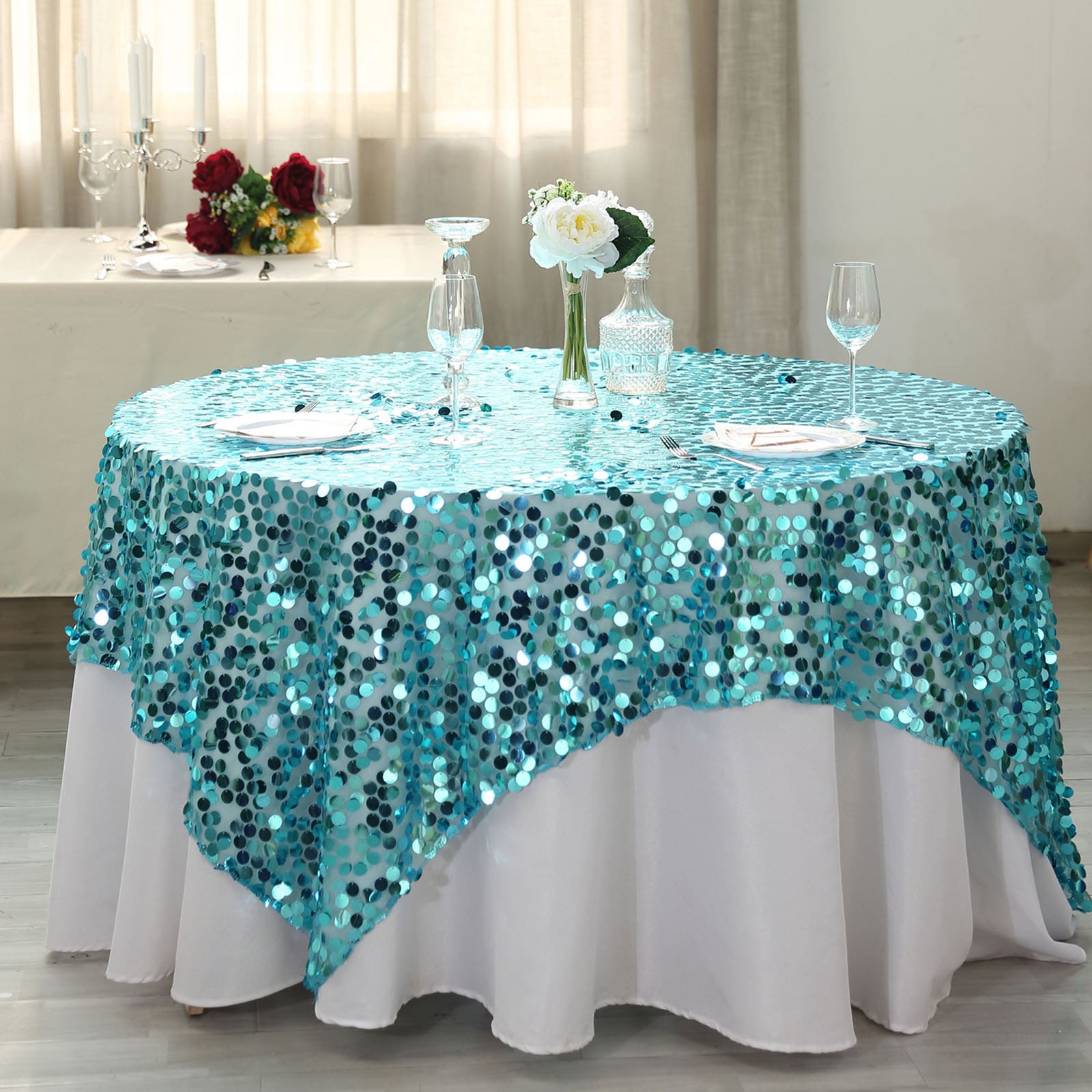 Turquoise sequin table overlay on a round table setting.