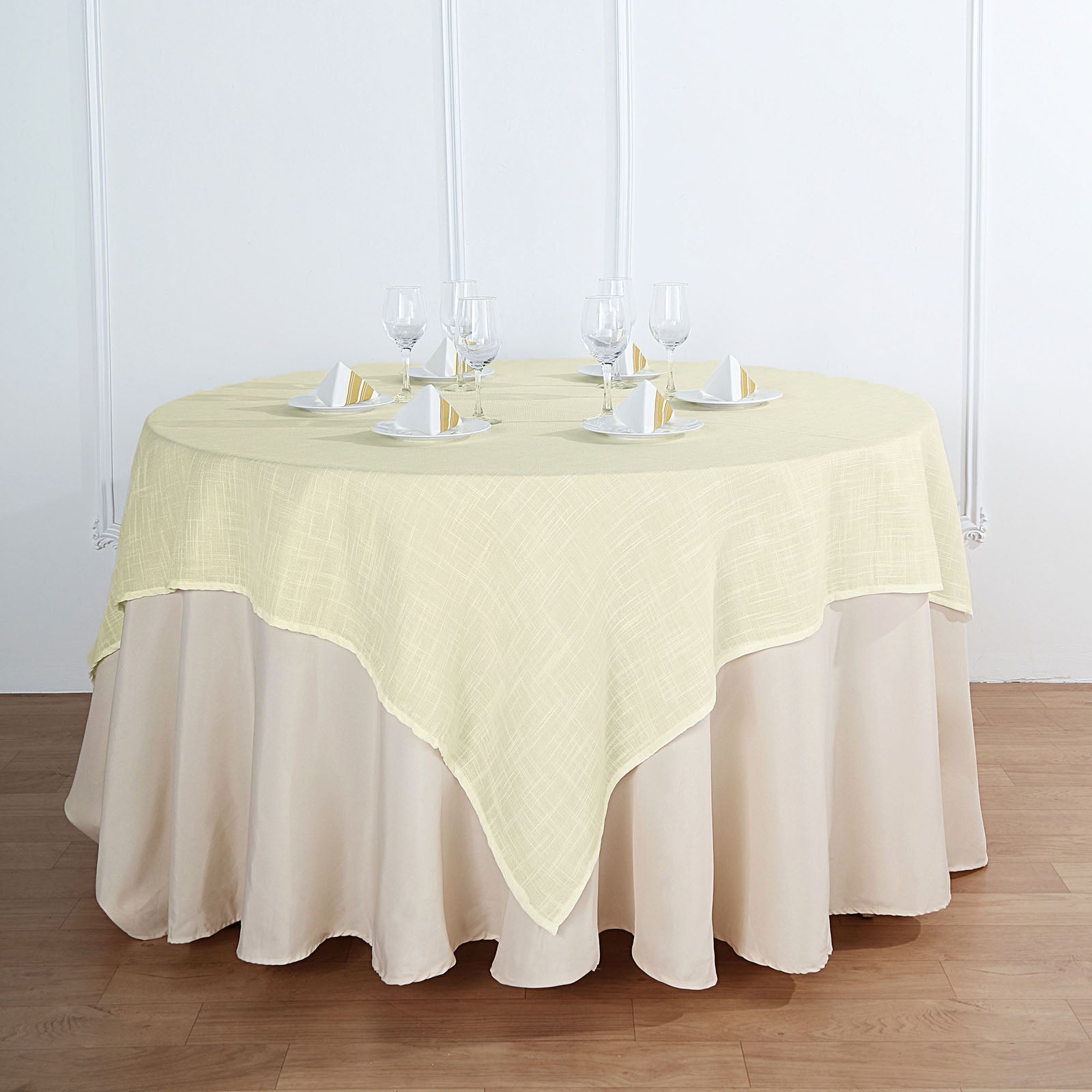 Ivory textured linen square table overlay on a round table.