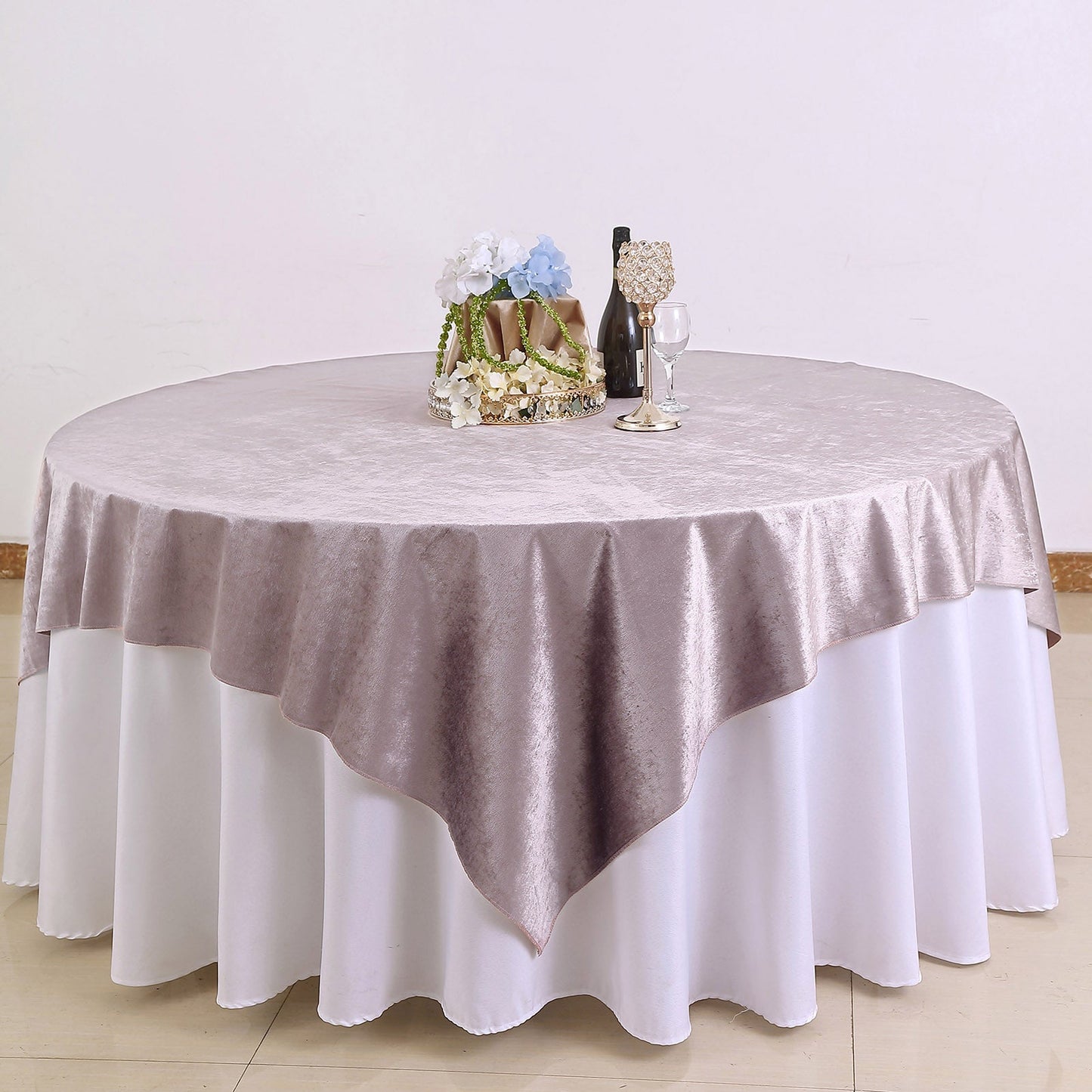 Mauve soft velvet table overlay on a round table with floral centerpiece.
