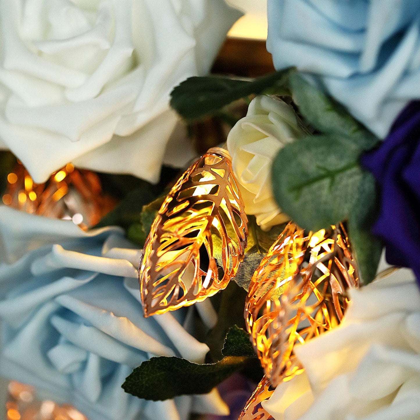 Rose gold leaves fairy string lights with warm white glow among roses.