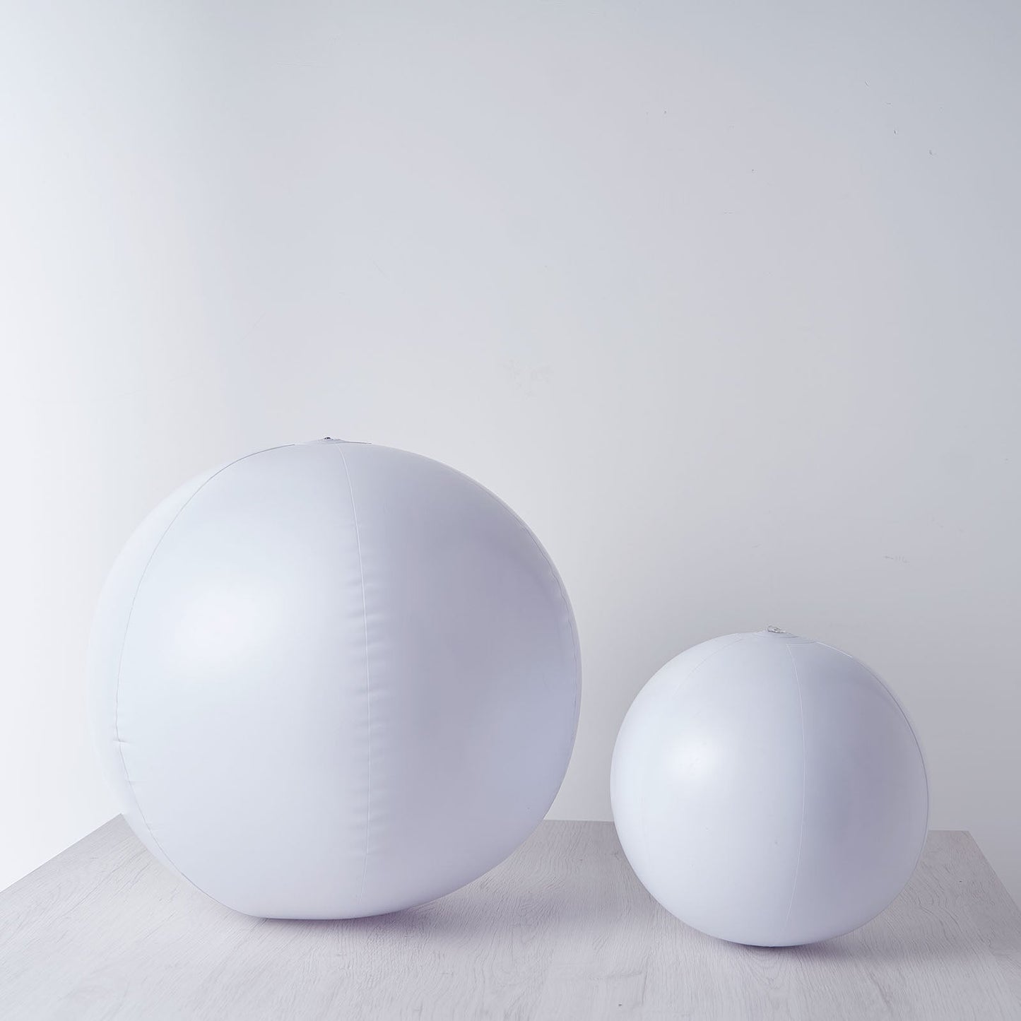 White inflatable garden glow balls on a wooden surface.