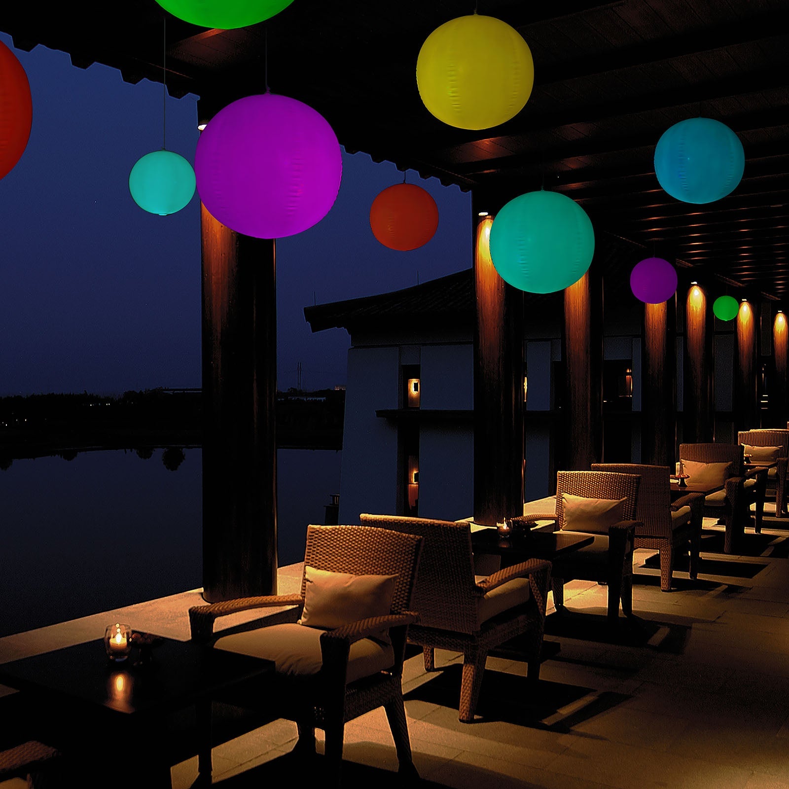 Colorful floating glow balls in an outdoor garden setting at night.