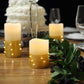 Gold LED pillar candles wrapped with fairy lights on a table setting.