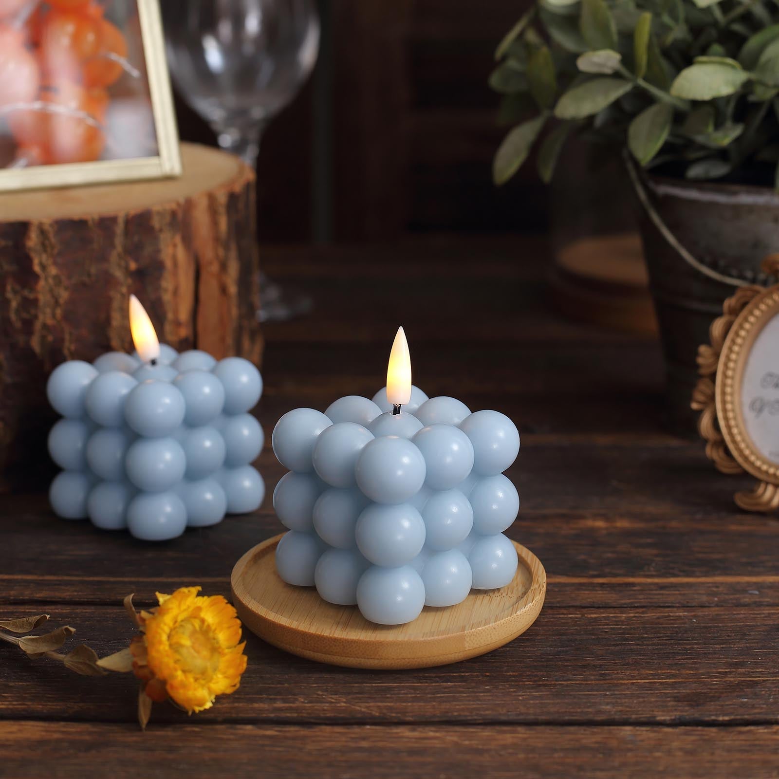 Dusty blue LED bubble candle on a wooden tray with warm white flickering flame.
