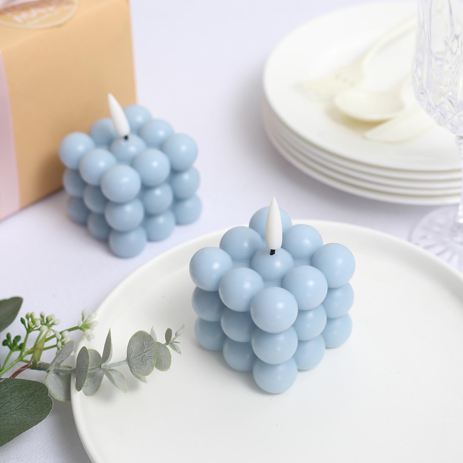 Dusty blue LED bubble candles on a white plate.