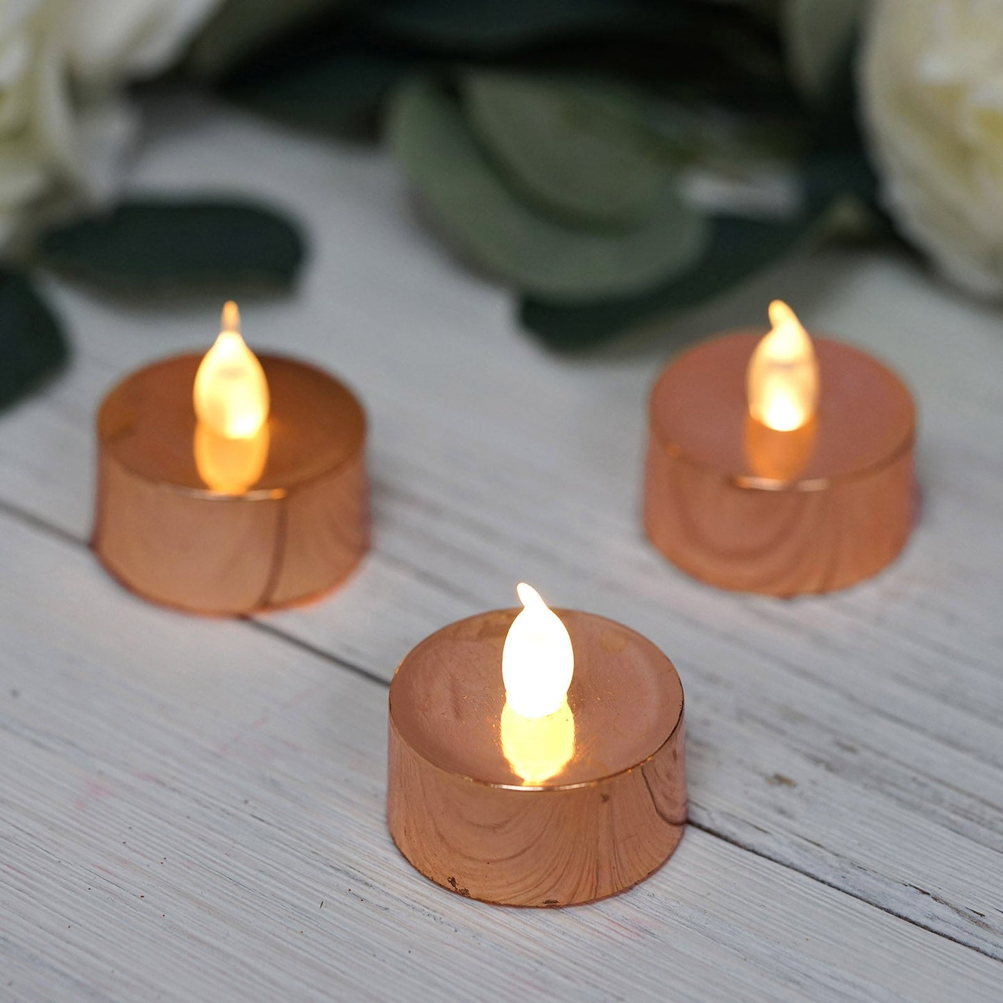 Metallic rose gold LED tealight candles with a warm glow.