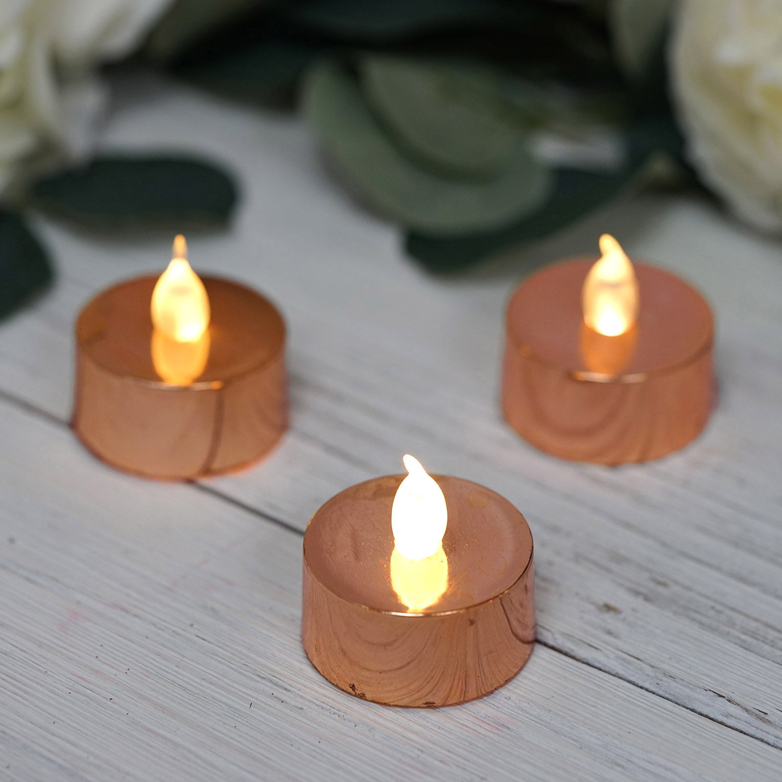Metallic rose gold LED tealight candles with a warm glow.
