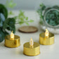 Metallic gold flameless LED tealight candles on a table.