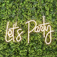 LED reusable neon light sign in warm white, hanging on greenery backdrop.