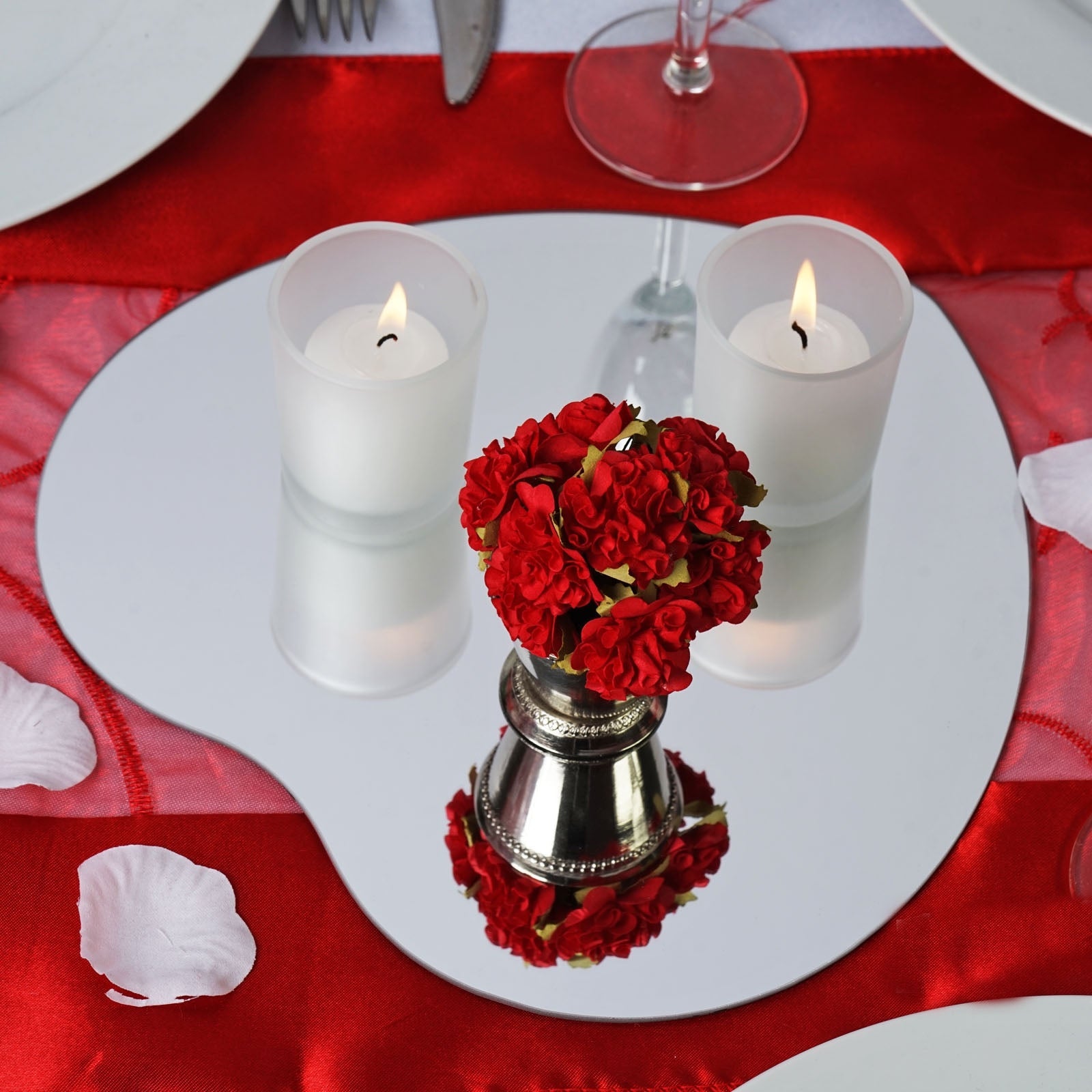 Red heart glass mirror centerpiece with candles and flowers.