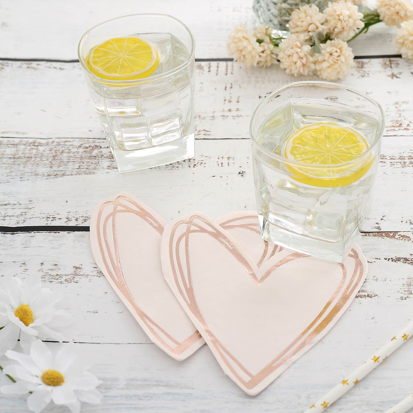Rose gold heart-shaped disposable cocktail napkins on a table.