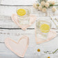 Rose gold heart-shaped cocktail napkins on a rustic table with drinks.